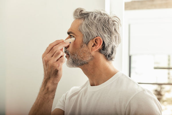 man applying eye stick for men in the guide to skin care